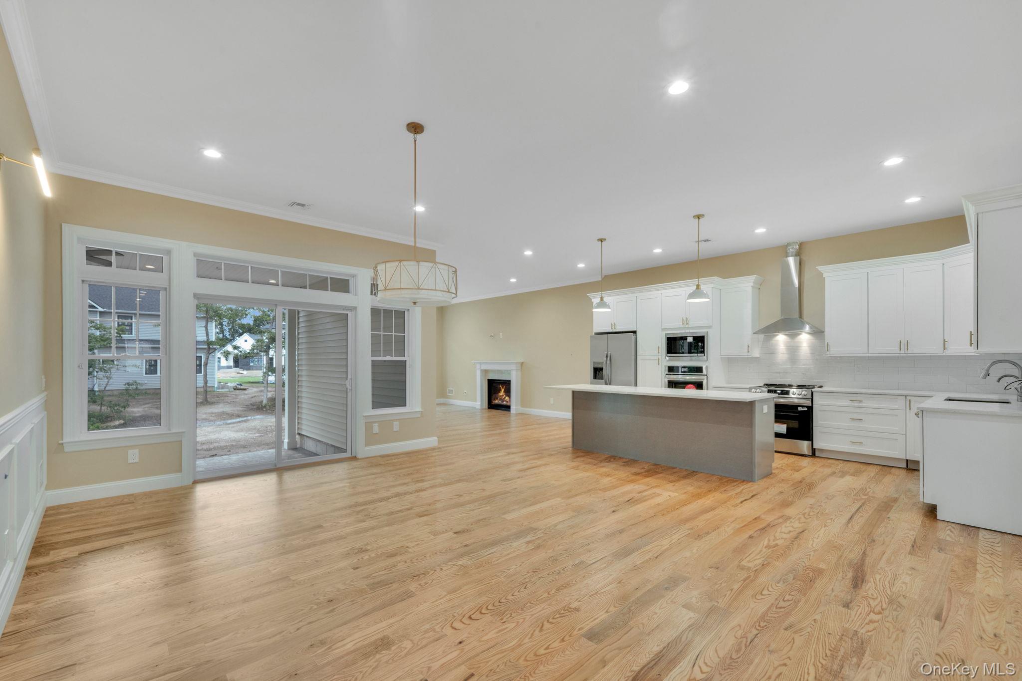 64 Blydenburgh Road Centereach, NY 11720 - Photo 27 of 29 a large kitchen with kitchen island a sink a stove a refrigerator and white cabinets with wooden floor