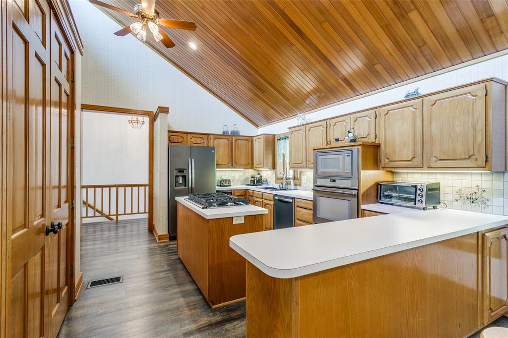 1557 Latigo Hills Road Bartonville, TX 75022 - Photo 9 of 40 Kitchen with light countertops, vaulted ceiling, a kitchen island, stainless steel appliances, and ceiling fan
