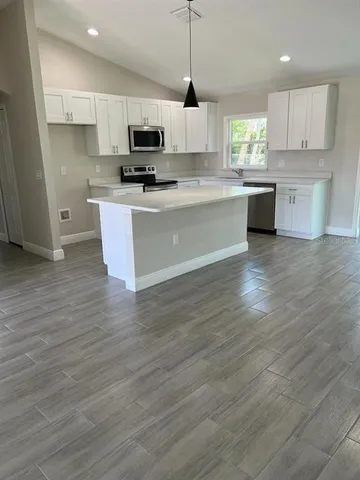 a large kitchen with stainless steel appliances granite countertop a stove a sink dishwasher and a microwave oven with wooden floor