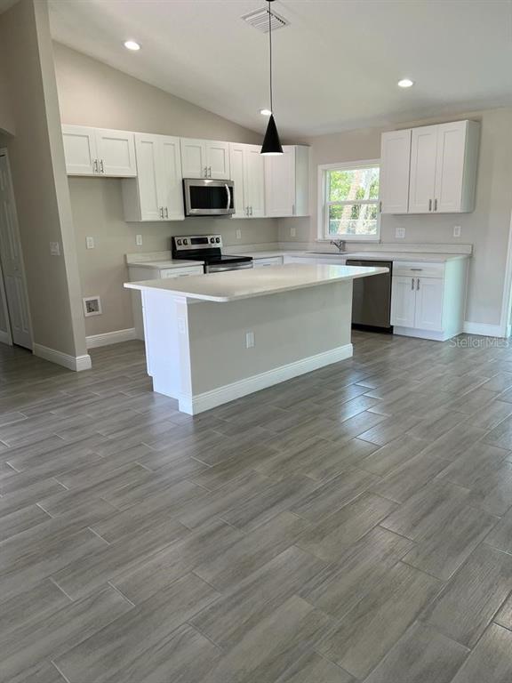 1042 Hickory Lane Cocoa, FL 32922 - Photo 2 of 8 a large kitchen with stainless steel appliances granite countertop a stove a sink dishwasher and a microwave oven with wooden floor