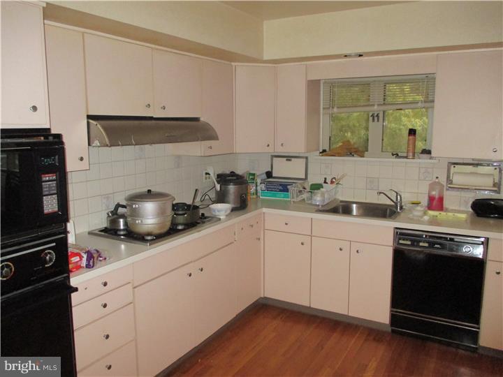 7943 Rolling Green Road Cheltenham, PA 19012 - Photo 8 of 25 a kitchen with white cabinets and a stove with wooden floor