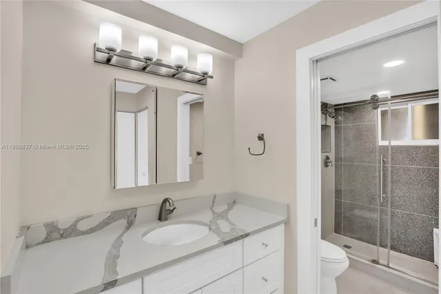 a bathroom with a granite countertop sink a toilet and a mirror