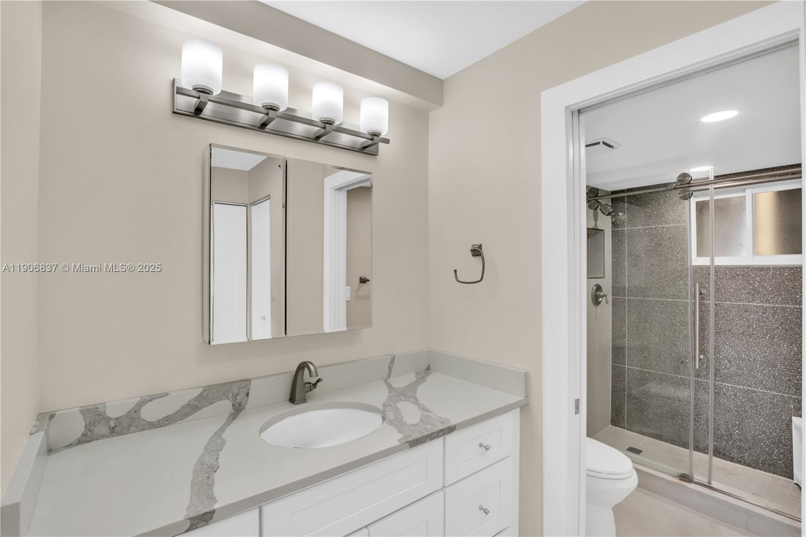 300 Ocean Trail Way, Unit 108 Jupiter, FL 33477 - Photo 11 of 21 a bathroom with a granite countertop sink a toilet and a mirror