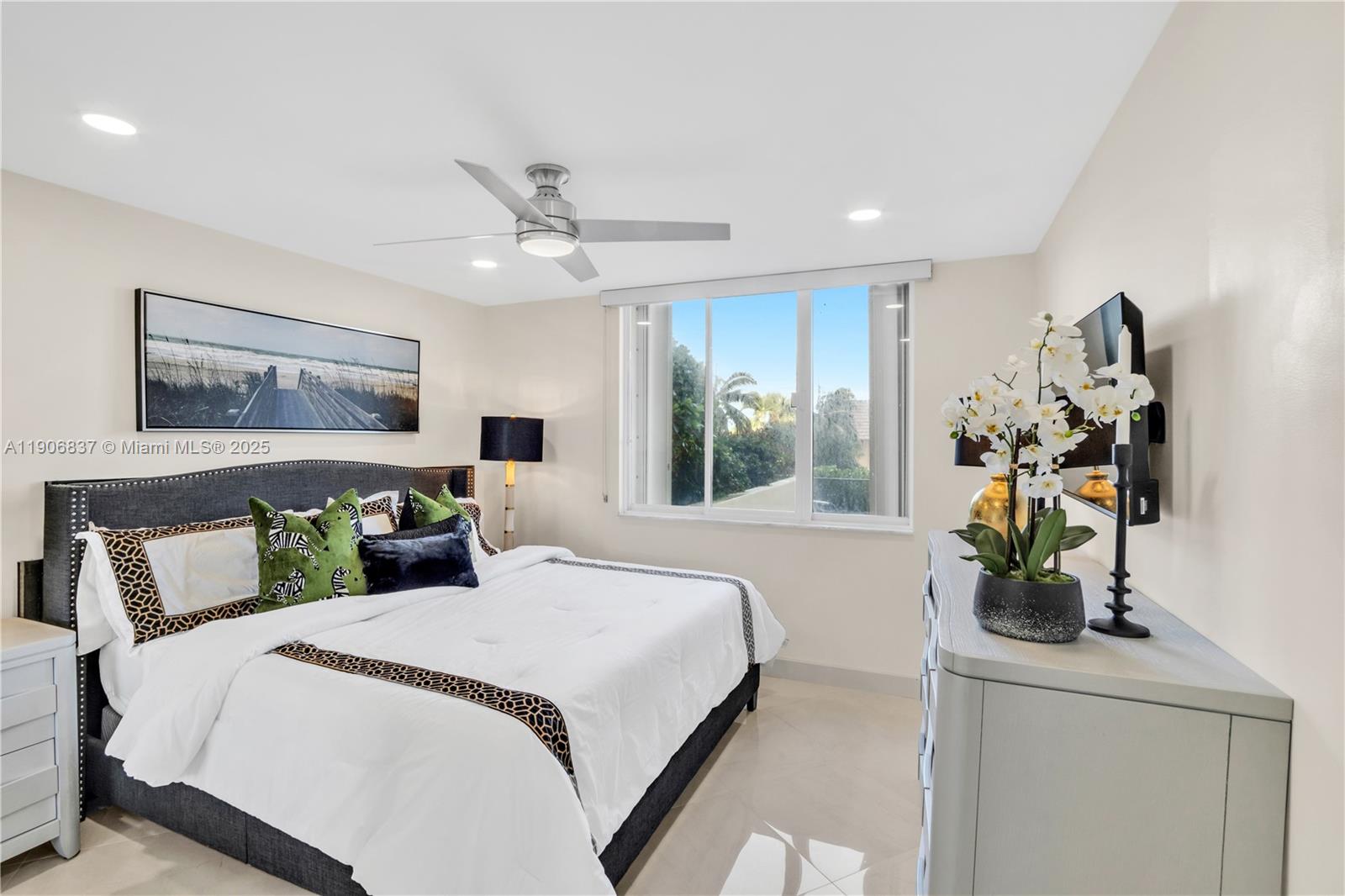 300 Ocean Trail Way, Unit 108 Jupiter, FL 33477 - Photo 13 of 21 a bedroom with a bed potted plant on the dresser and a chandelier