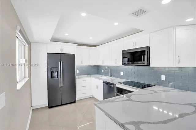 a kitchen with stainless steel appliances kitchen island granite countertop a refrigerator a sink a stove and oven with wooden floor