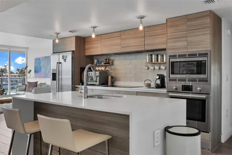 a kitchen with stainless steel appliances a dining table chairs microwave and cabinets