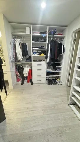 a view of walk in closet with clothes and shoes