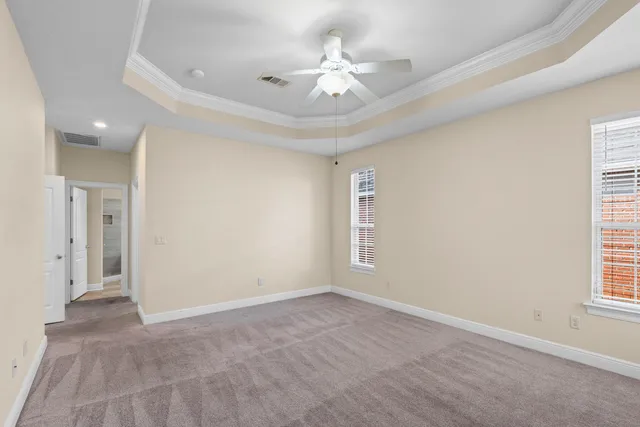 an empty room with windows and ceiling fan