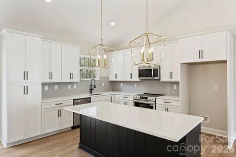 a kitchen that has a lot of white cabinets and stainless steel appliances