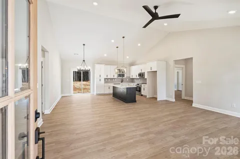 a view of a kitchen with kitchen island wooden floor center island stainless steel appliances and windows