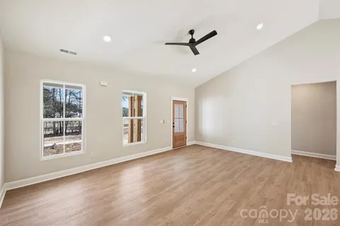 a view of empty room with wooden floor and fan