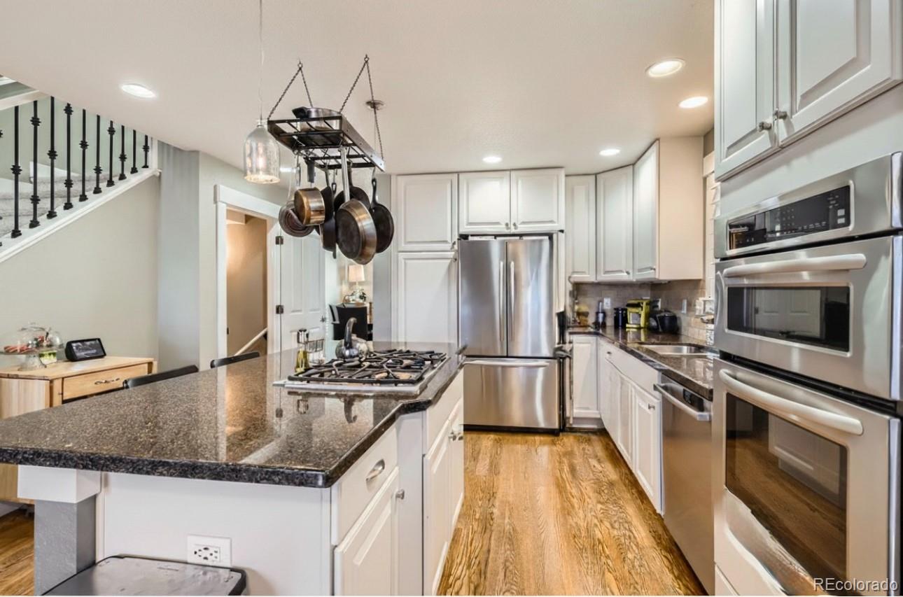 1145 South Logan Street Denver, CO 80210 - Photo 6 of 21 a kitchen with stainless steel appliances granite countertop a sink dishwasher a refrigerator and a stove with wooden floor