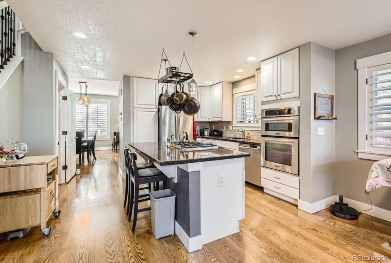 1145 South Logan Street Denver, CO 80210 - Photo 7 of 21 a kitchen with stainless steel appliances kitchen island hardwood floor and a sink
