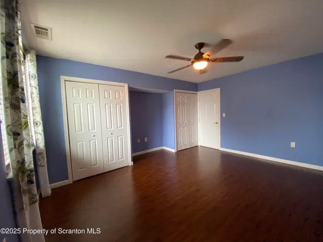 a view of an empty room with window and wooden floor