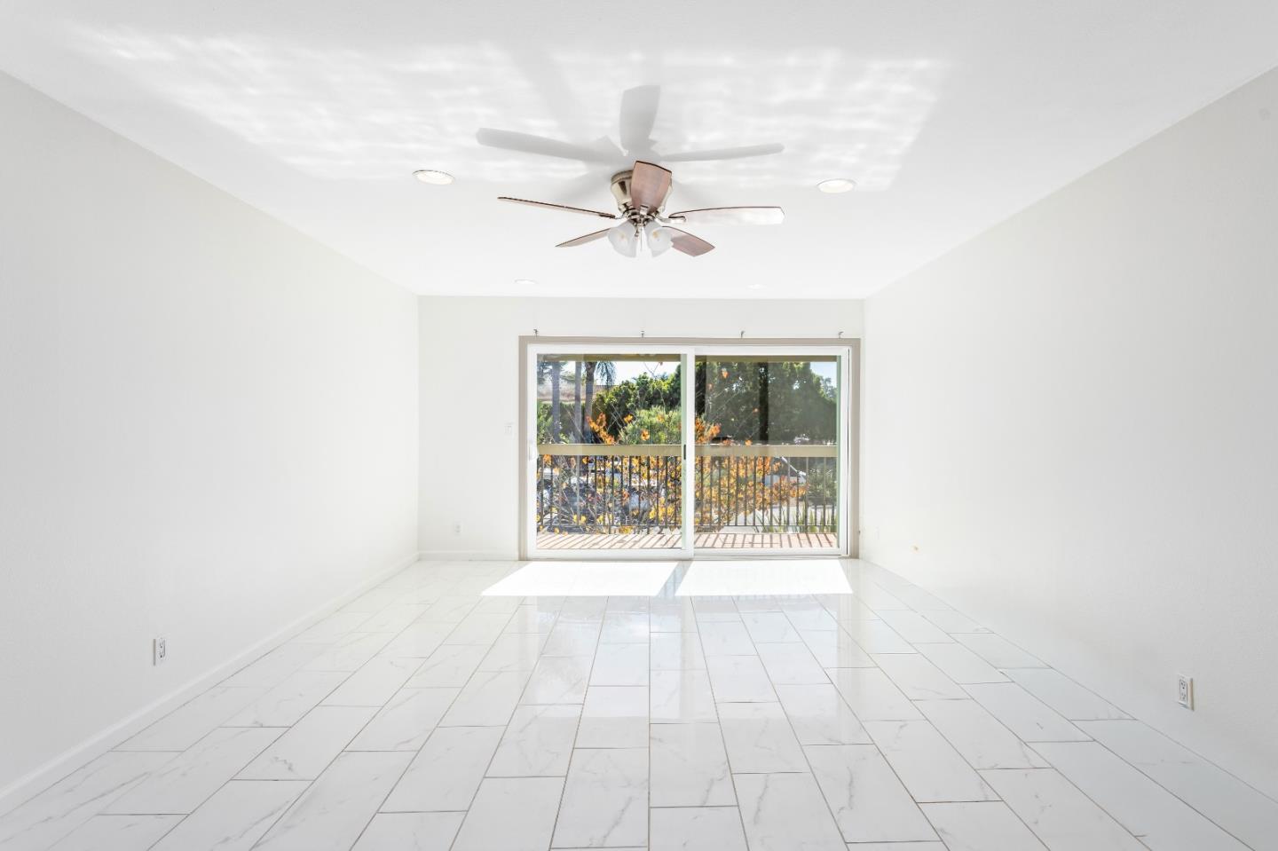 an empty room with windows and fan