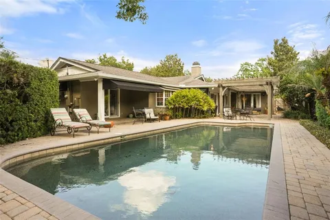 a view of house with swimming pool and outdoor seating