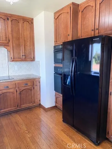 a kitchen with stainless steel appliances granite countertop a refrigerator a sink and dishwasher with wooden cabinets