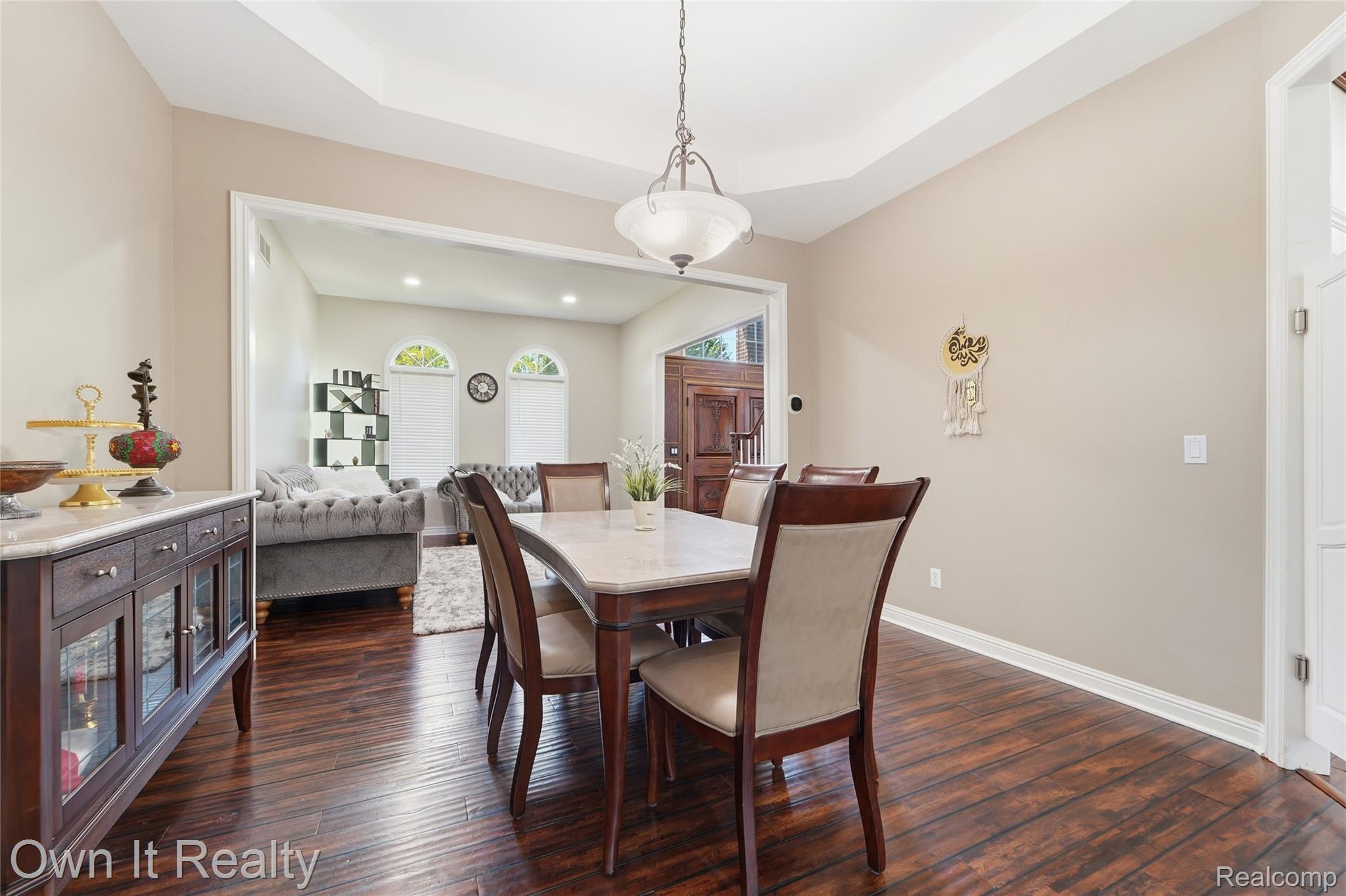 48280 Gladstone Road Canton, MI 48188 - Photo 12 of 59 Dining area featuring wood-finish flooring, a tray ceiling with a hanging light fixture, and an expansive entry to an adjoining living space with arched windows