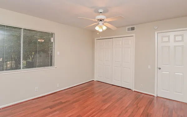 a view of an empty room with wooden floor and a window