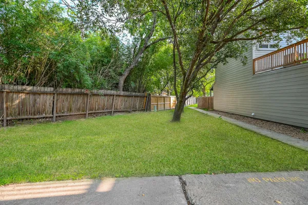 a view of a backyard with large trees and wooden fence