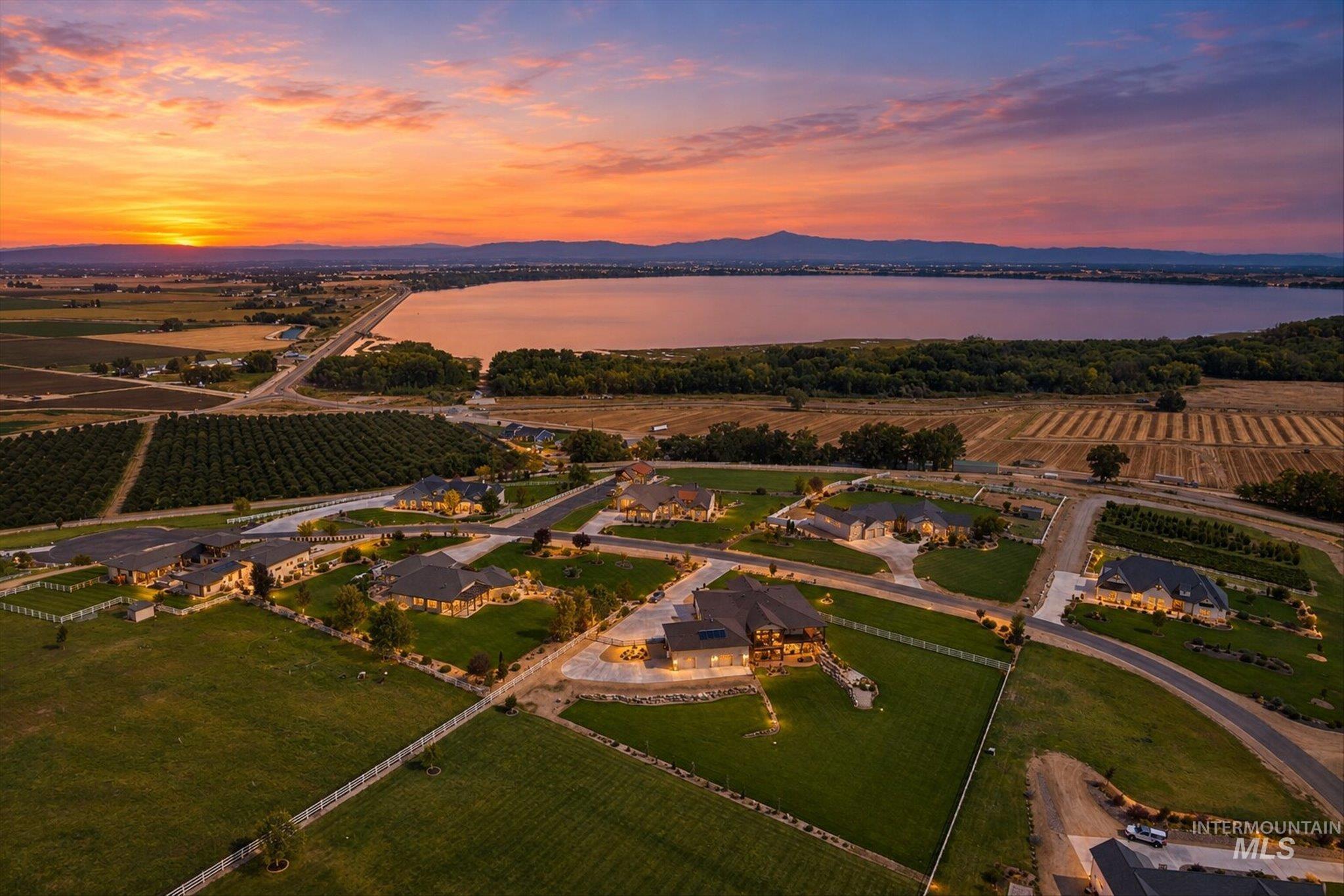 Expansive residential area featuring a large body of water, distant mountains, and agricultural land