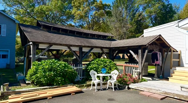 a view of a patio with table and chairs potted plants and large tree