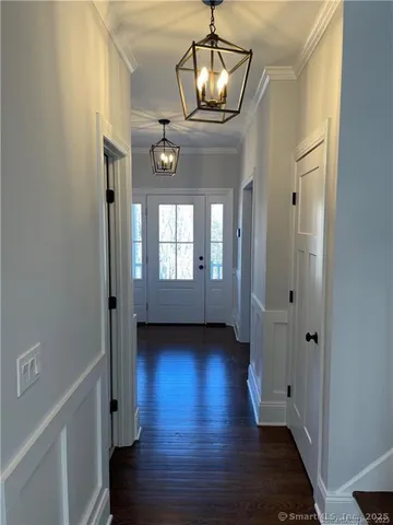a view of hallway with chandelier and wooden floor