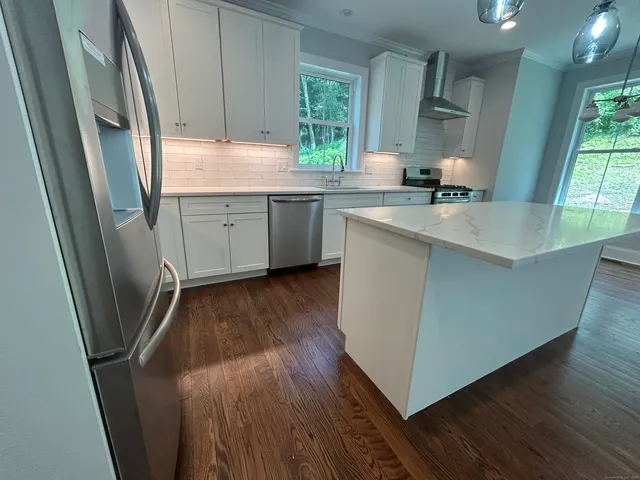 a kitchen with stainless steel appliances a refrigerator a sink a stove a microwave a sink and wooden floor