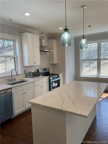 a kitchen with stainless steel appliances a sink a window and cabinets