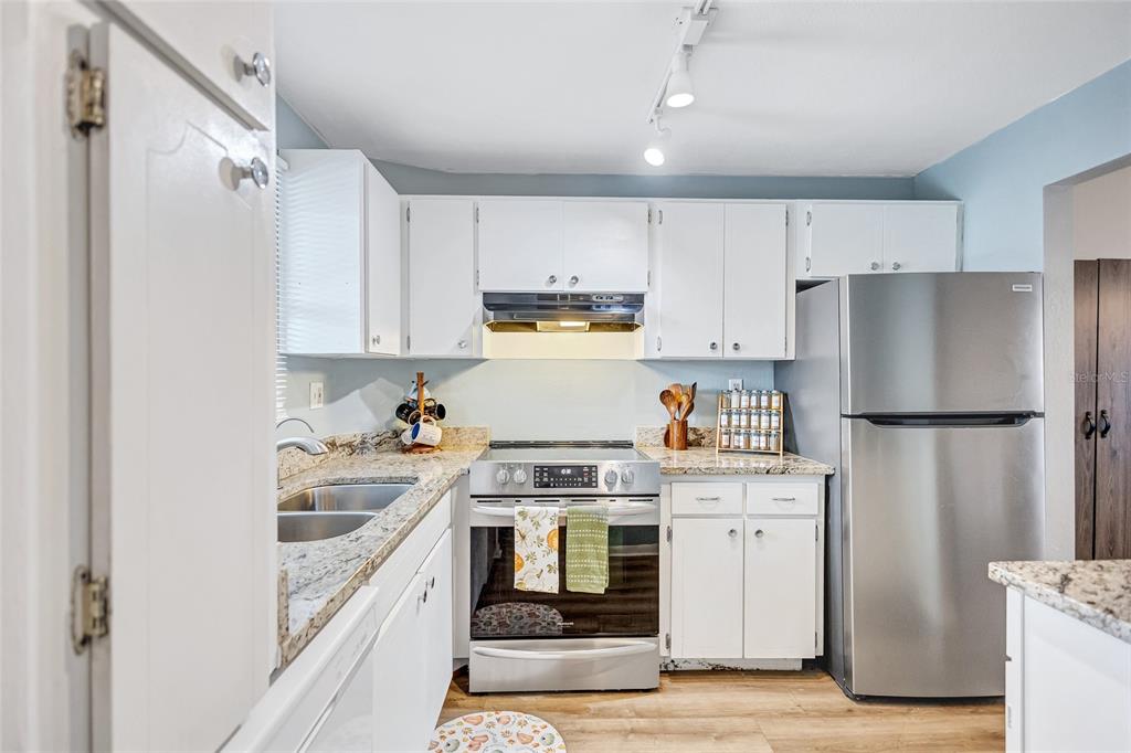 3125 36th Street North, Unit 208 St. Petersburg, FL 33713 - Photo 5 of 29 a kitchen with white cabinets and stainless steel appliances