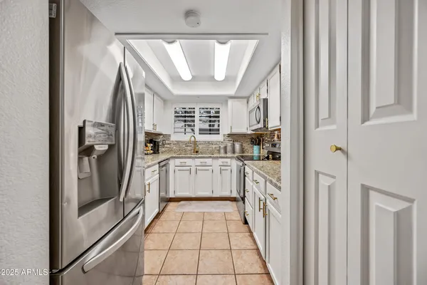 a kitchen with granite countertop stainless steel appliances white cabinets sink and dishwasher