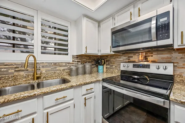 a kitchen with stainless steel appliances granite countertop a sink stove and cabinets