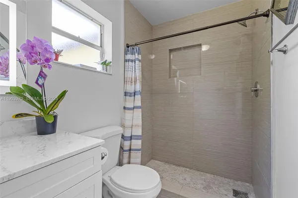 a bathroom with a granite countertop sink a toilet and shower