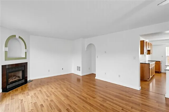 a view of empty room with wooden floor and fireplace