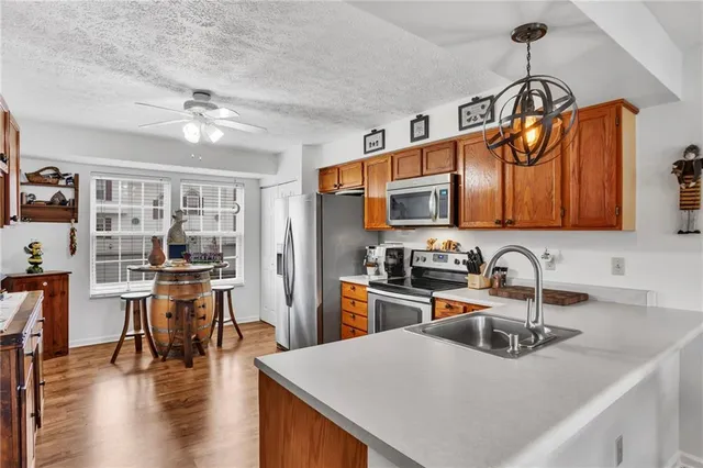 a kitchen with stainless steel appliances granite countertop a sink a stove top oven a chimney cabinets and dining table