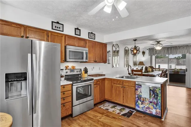 a kitchen with stainless steel appliances granite countertop a refrigerator a sink dishwasher a stove with wooden cabinets and floor