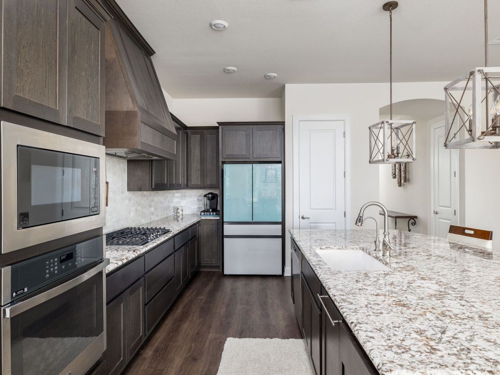 1145 West County Road East Lexington, TX 78947 - Photo 9 of 34 a kitchen with stainless steel appliances granite countertop a sink a stove and a wooden floors