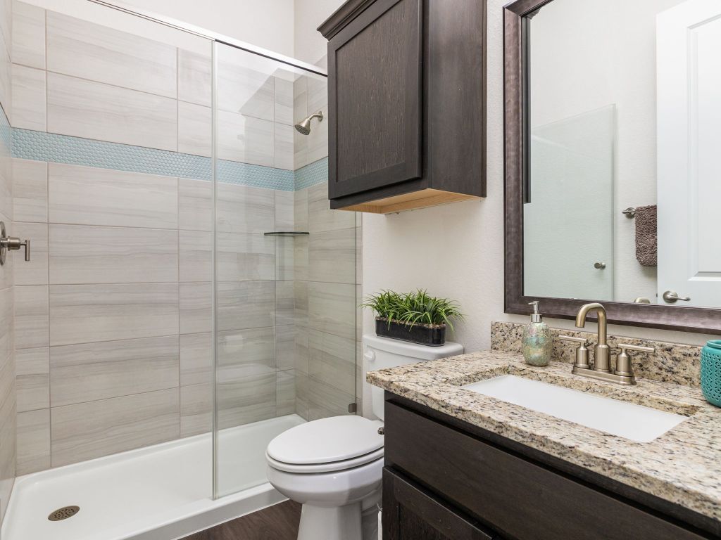 1145 West County Road East Lexington, TX 78947 - Photo 18 of 34 a bathroom with a granite countertop sink a toilet and a mirror