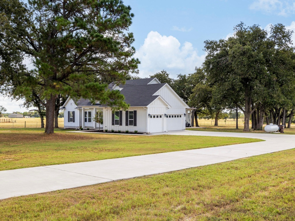1145 West County Road East Lexington, TX 78947 - Photo 3 of 34 a front view of a house with a yard and a large tree
