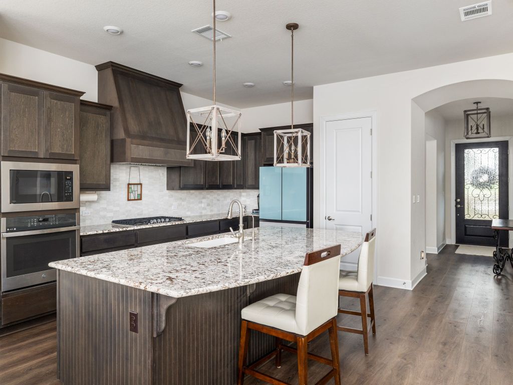 1145 West County Road East Lexington, TX 78947 - Photo 7 of 34 a kitchen with granite countertop a table chairs stainless steel appliances and wooden floor