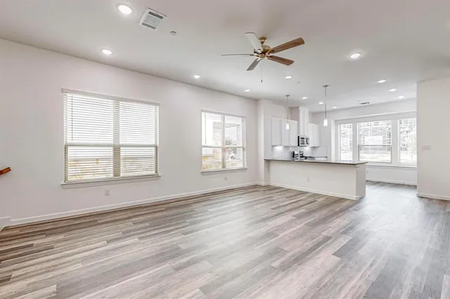 a view of an empty room with a window and wooden floor