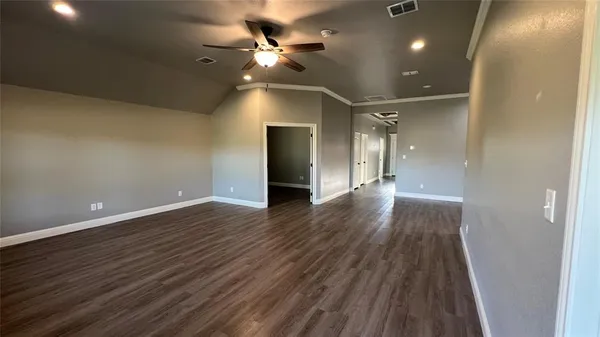 an empty room with wooden floor and a ceiling fan