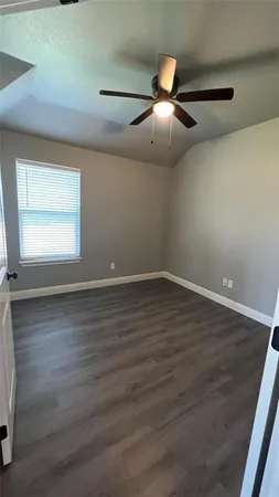 an empty room with wooden floor chandelier fan and windows
