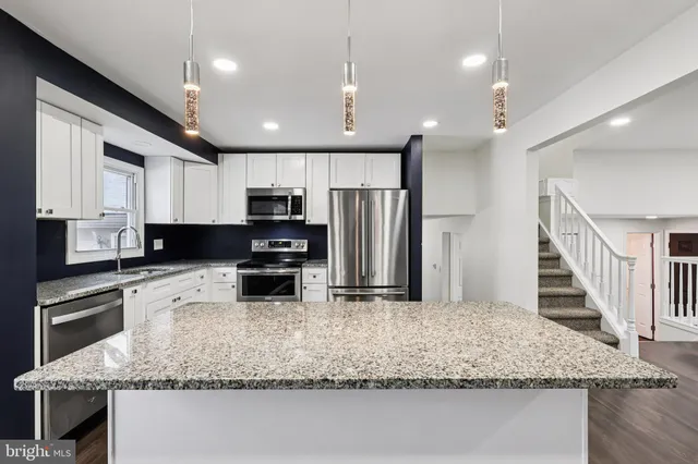 a kitchen with kitchen island granite countertop stainless steel appliances sink stove microwave and cabinets