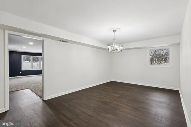 a view of an empty room with wooden floor and a ceiling fan