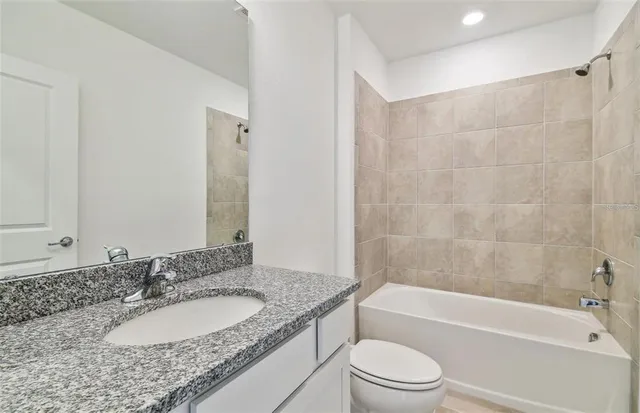 a bathroom with a granite countertop sink toilet and bathtub