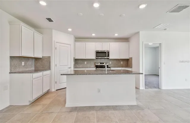 a large kitchen with stainless steel appliances lots of white cabinets