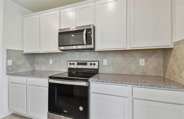 a kitchen with granite countertop white cabinets and stainless steel appliances