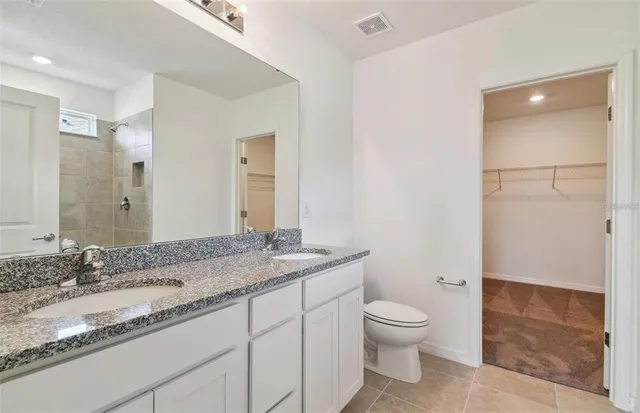 a bathroom with a granite countertop sink a toilet and a shower
