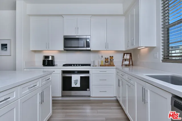 a kitchen with stainless steel appliances granite countertop white cabinets granite counter tops and a hard wood floors